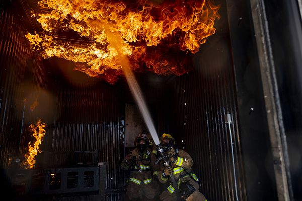 Staff Sgt. Alex Urrutia, 99th Civil Engineering Squadron lead fire protection specialist, extinguishes a fire during structural fire training at Nellis Air Force Base, Nev., Sept. 18, 2023. The training tests firefighters’ skills to search a burning building and successfully put out the fire and evaluates teamwork and safety protocols. (U.S. Air Force photo by Senior Airman Zachary Rufus) 