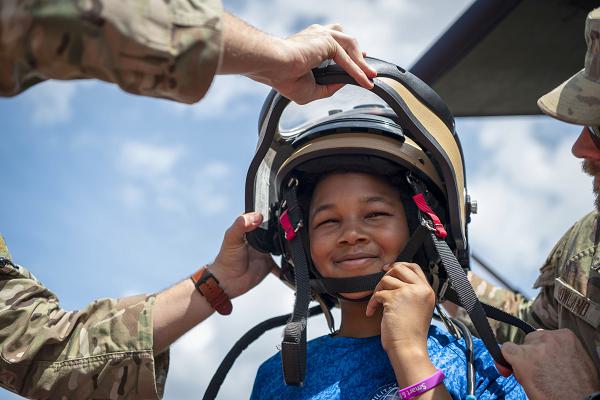 A student from Tinker K-8 tries on a 6th Civil Engineer Squadron explosive ordnance device helmet during a Contingency and Readiness Education Simulation at MacDill Air Force Base, Florida, April 3, 2025. The Military and Family Readiness Center organized the event to help children understand what their parents might experience before and during a deployment. As part of the kid-friendly activities, several squadrons from around base were able to demonstrate what they do day-to-day. (U.S. Air Force photo by Airman 1st Class Alicia Campbell)
