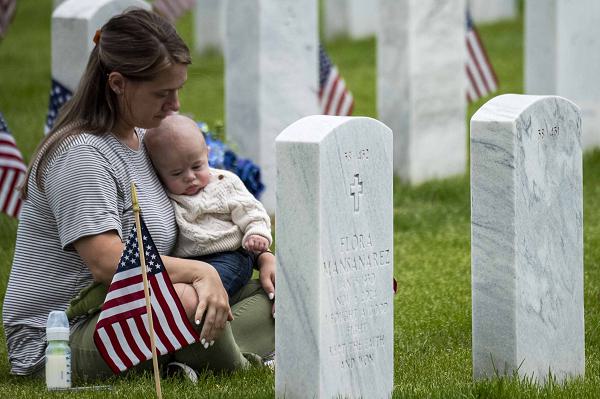 Mikeala Plaszcz and her child visit the resting place of her father following a flyover from F-16C Vipers from the 120th Fighter Squadron, Colorado Air National Guard, at Fort Logan National Cemetery, May 26, 2025. Flyover times are coordinated with event staff and are conducted at no additional cost to the taxpayer, serving as training for our pilots. (U.S. Air National Guard photo by Tech. Sgt. Chance Johnson)