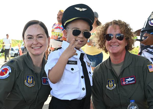 Col. Elissa Granderson, 403rd Operations Group commander and pilot, and Lt. Col. Devon Burton, 53rd Weather Reconnaissance Squadron pilot, pose for a photo with one enthusiastic youth during the Caribbean Hurricane Awareness Tour at Aguadilla, Puerto Rico, April 20, 2024. NOAA hurricane specialists and the U.S. Air Force Reserve Hurricane Hunters discussed hurricane preparedness, resilience and how people can become “weather-ready” during the event. (U.S. Air Force photo by Lt. Col. Marnee A.C. Losurdo) 