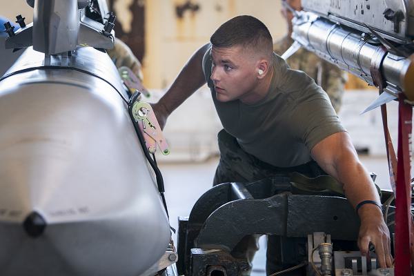 Staff Sgt. Jacob Leasum, 96th Aircraft Maintenance Squadron Blue, guides a GBU-31 bomb into place during the first quarter weapons load crew competition, April 12, 2024, at Eglin Air Force Base, Fla. The fast-paced competition pitted the F-16 Fighting Falcon team against the F-15 Eagle team in an assessment of their knowledge, proficiency, speed and skill. (U.S. Air Force photo by Samuel King Jr.) 