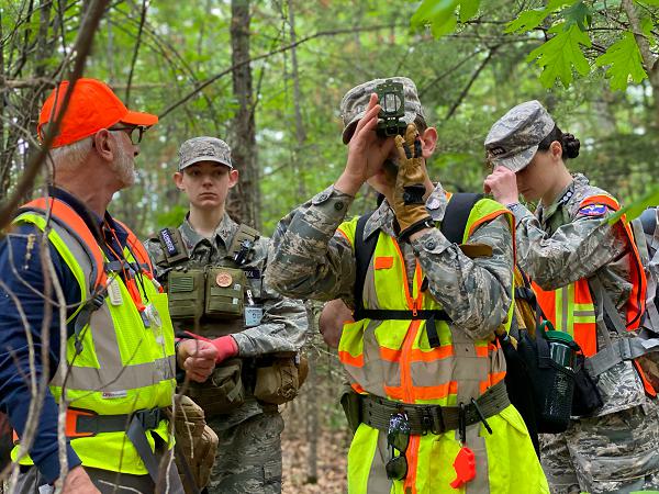 Cadet Staff Sgt. Samuel Renda utilizes a compass during a ground team search while Maj. Ralph Gamache, Cadet Capt. Caroline Benson, and Cadet Senior Airman Travis Kaemmerer listen and scan for the subject.