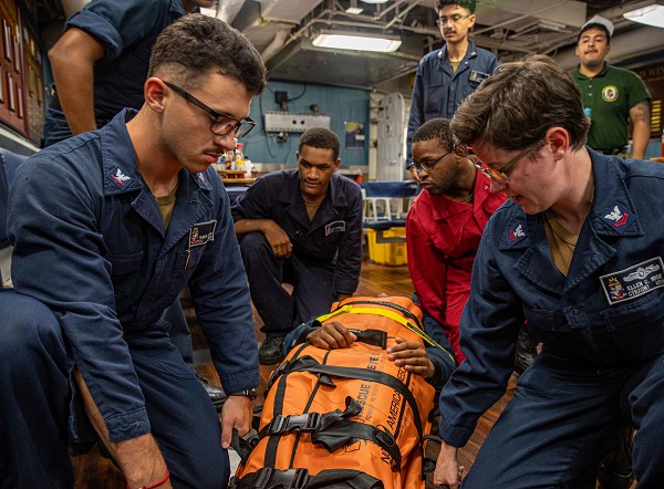 Aboard the USS Chancellorsville, South China Sea. (July 28, 2022): In this photo by Petty Officer 2nd Class Justin Stack, sailors conduct stretcher bearer training for a mass casualty event in the event of an emergency. A sailor’s life is filled constant training, long hours, and plenty of stresses and frustrations. 